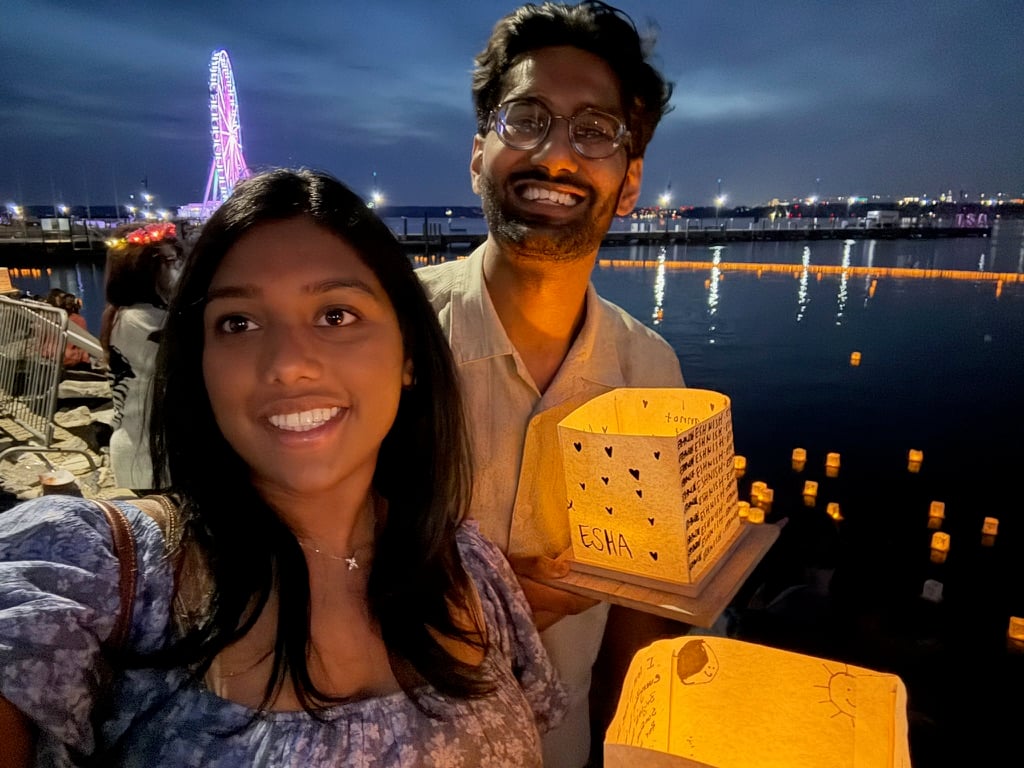Esha & Anish holding a glowing paper lantern at a water lantern festival
