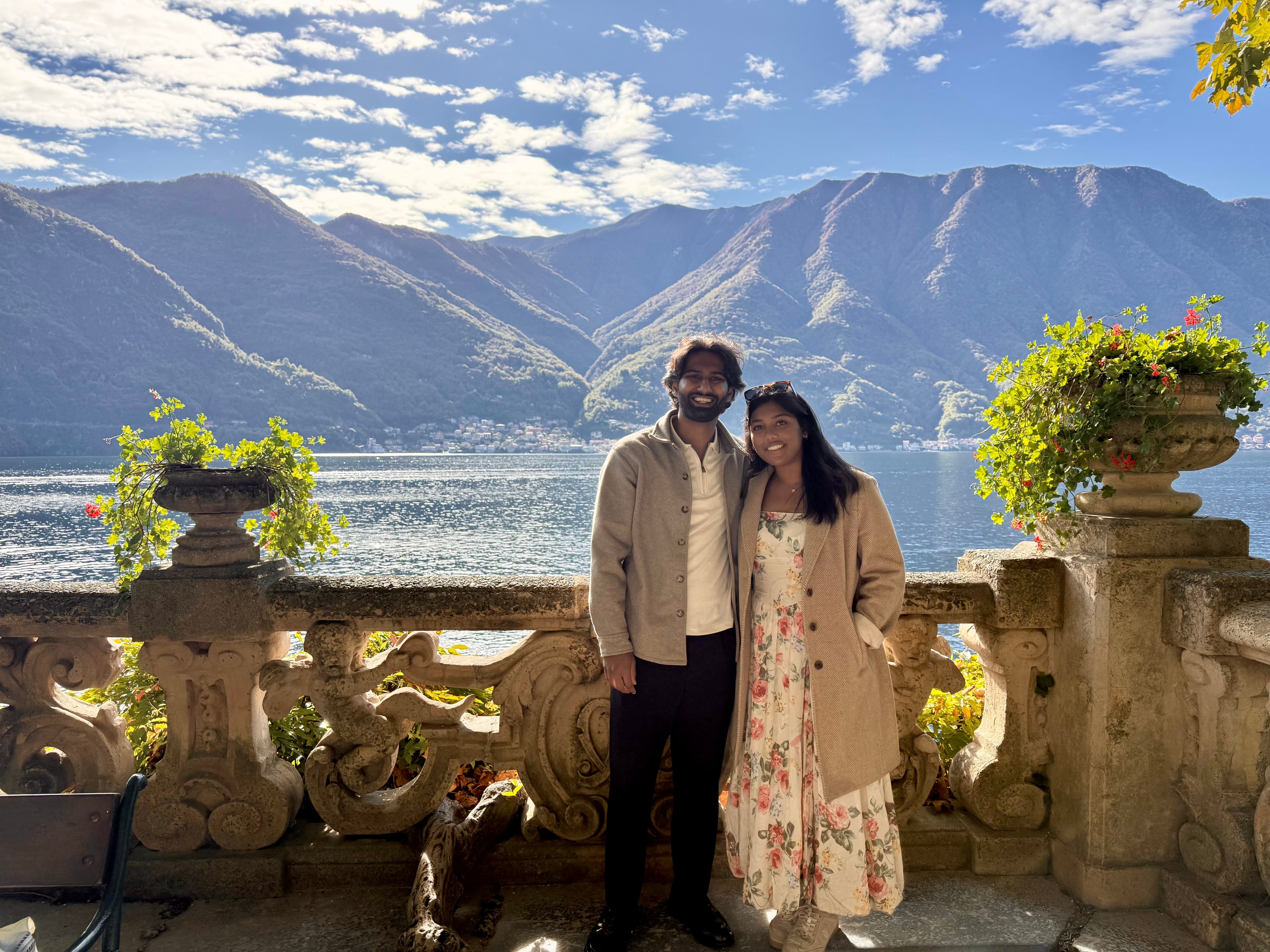 Esha and Anish standing together by Lake Como with mountain views