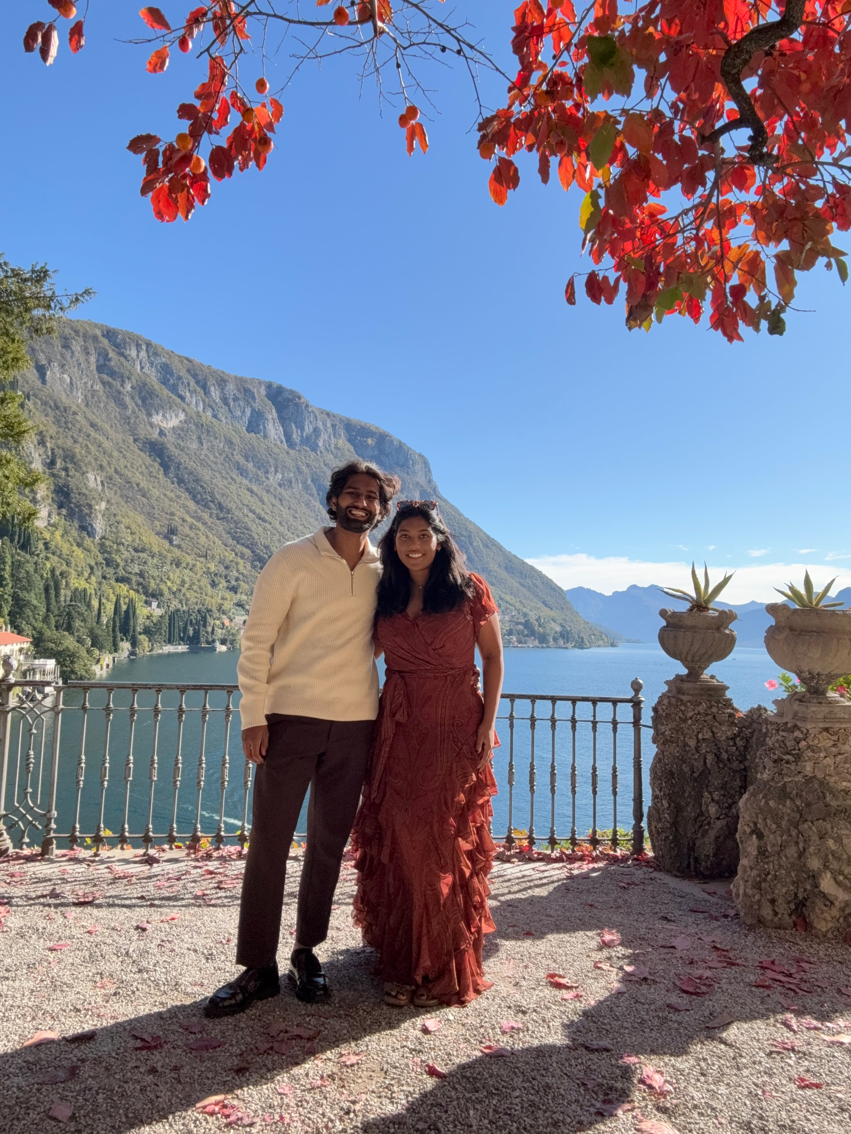 Esha and Anish standing together on a balcony overlooking Lake Como before the proposal